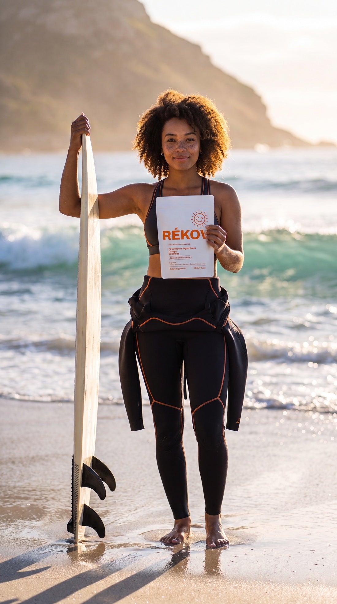 Surfer holding Rékov recovery gummies at the beach
